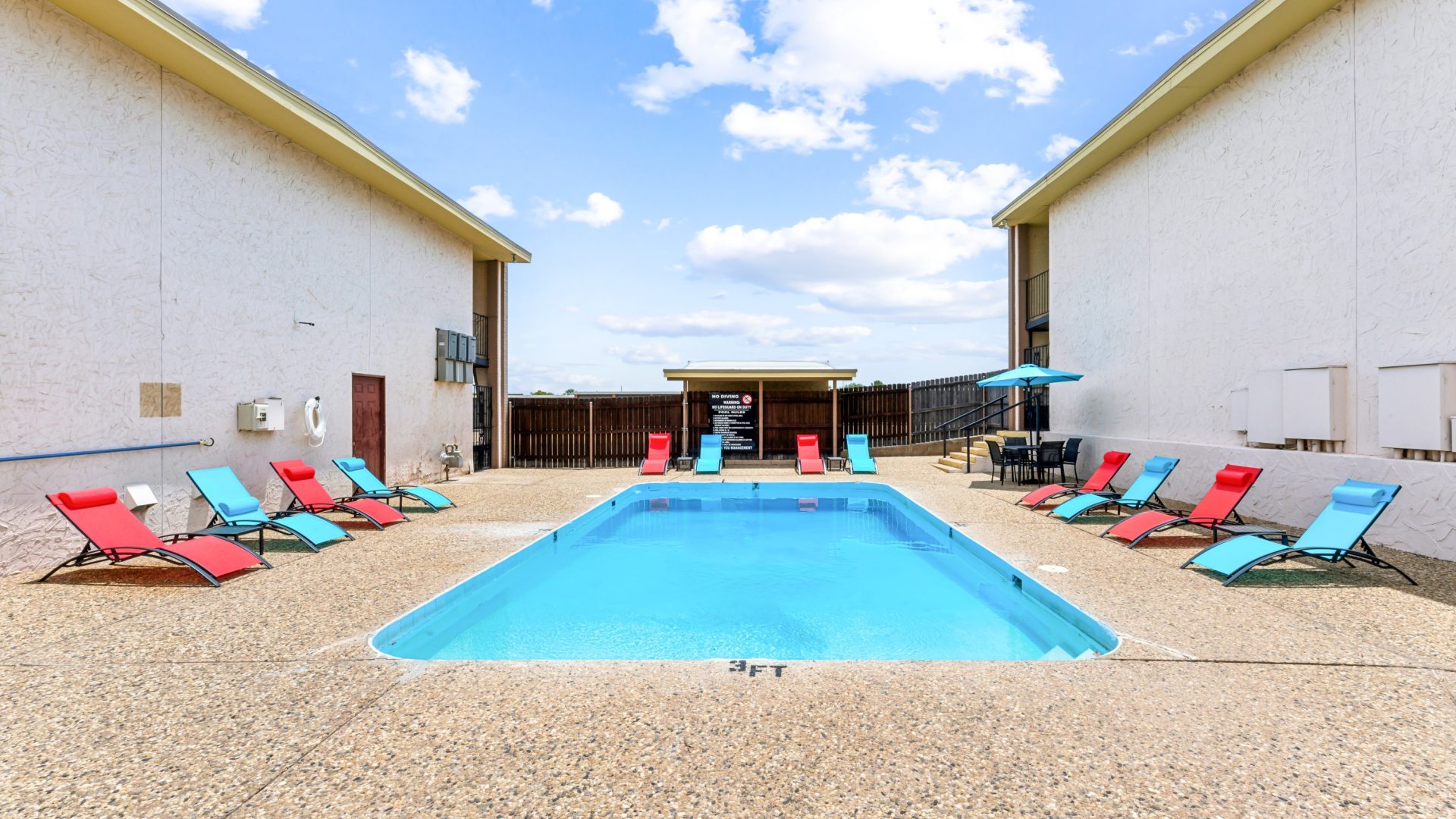 a pool with lounge chairs and a patio area at The Alamo Village Apartments