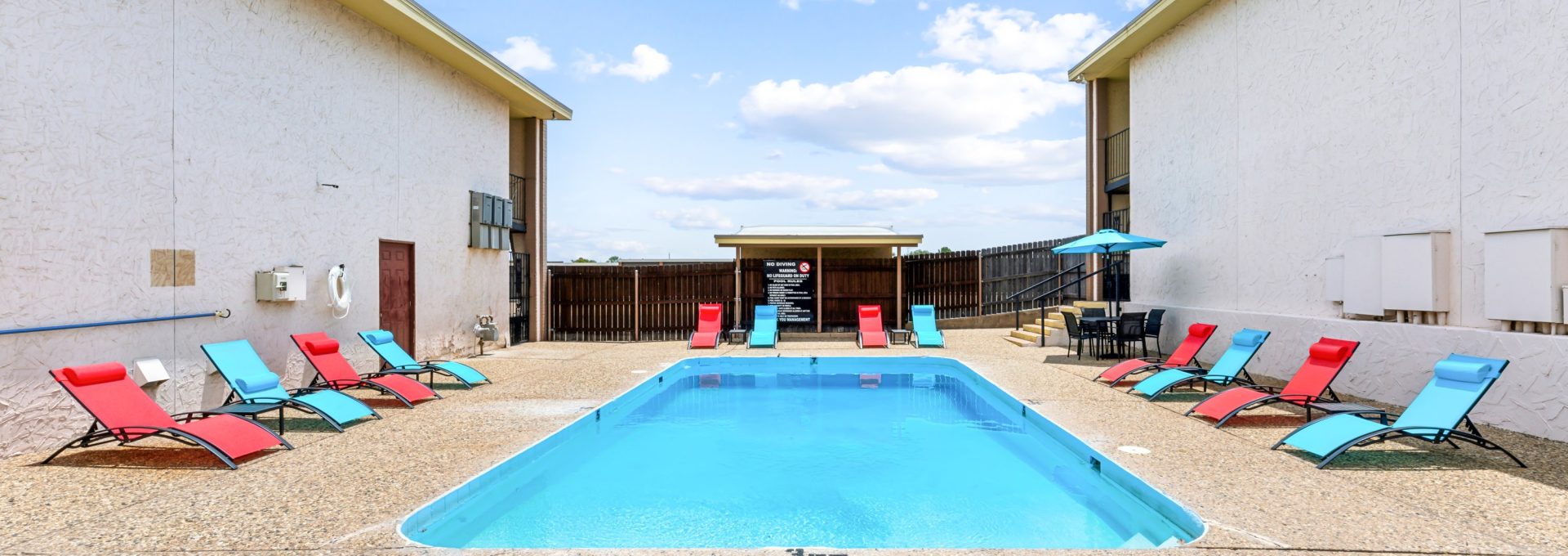 a pool with lounge chairs and a patio area at The Alamo Village Apartments