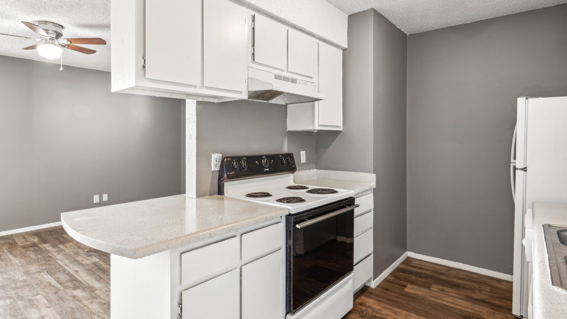 a kitchen with white cabinets and gray appliances at The Alamo Village Apartments