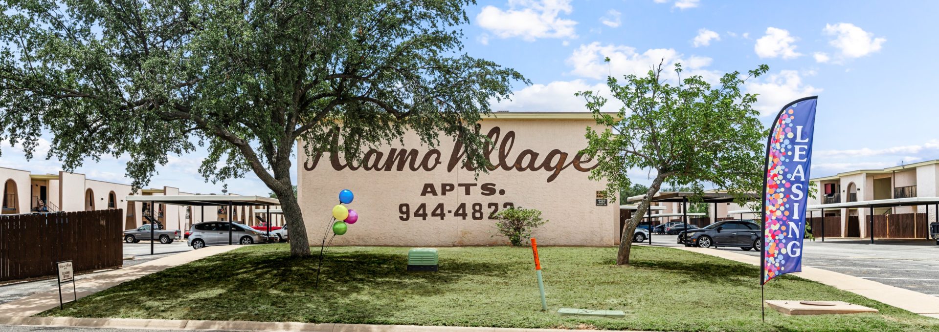 the sign for the village apartments in san antonio at The Alamo Village Apartments