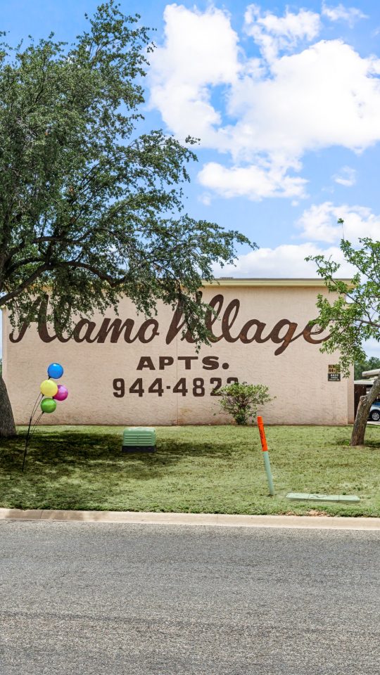 the sign for the village apartments in san antonio at The Alamo Village Apartments