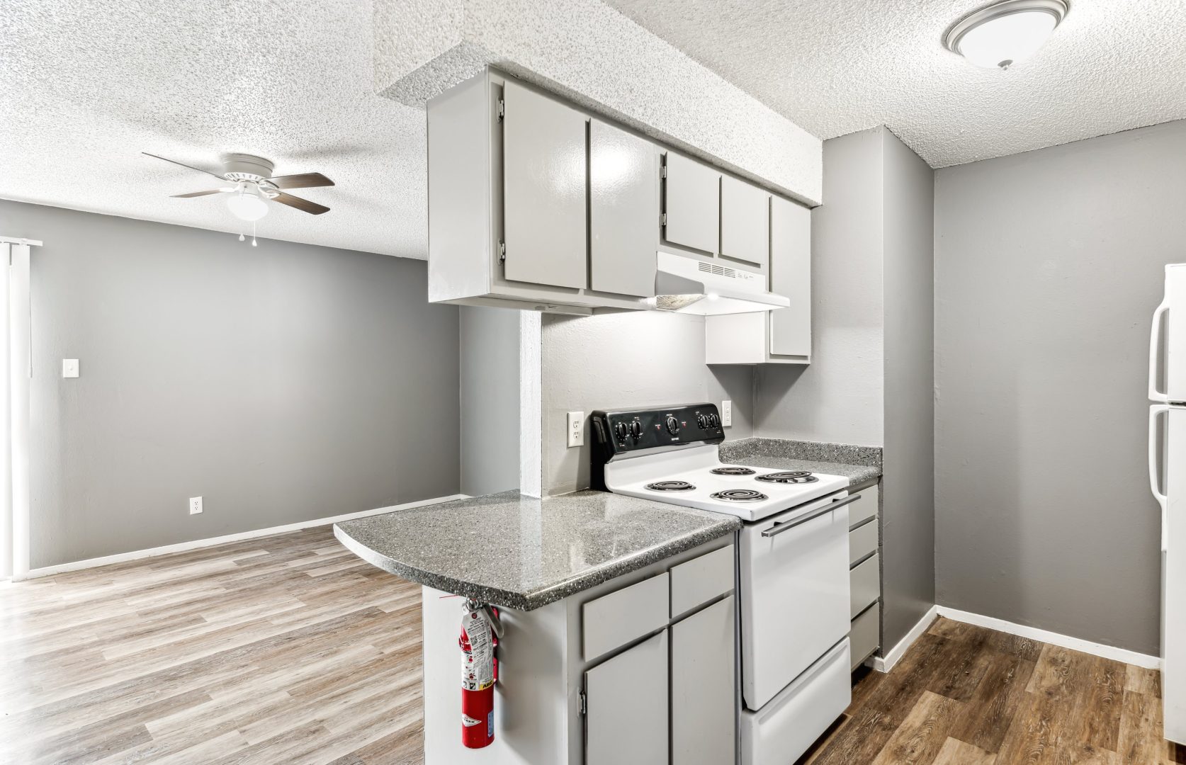 a kitchen with white cabinets and stainless steel appliances at The Alamo Village Apartments