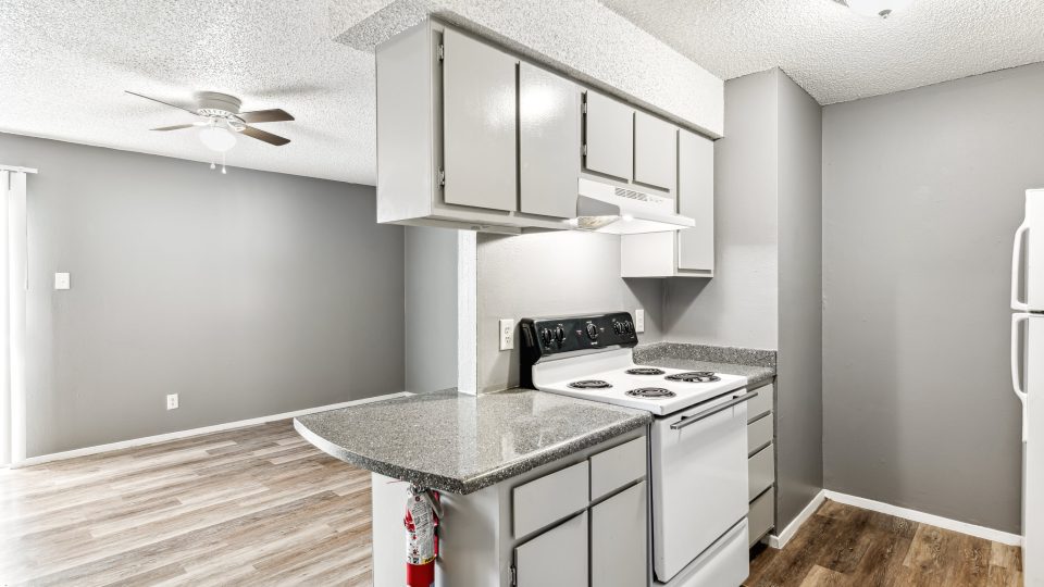 a kitchen with white cabinets and stainless steel appliances at The Alamo Village Apartments